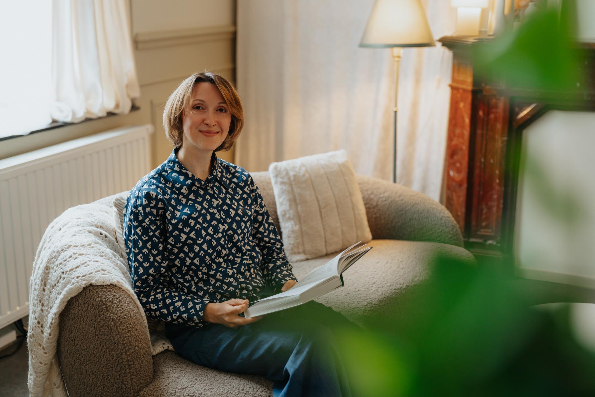 Vrouw leest ontspannen in een warm interieur: zelfzorg en zelfcompassie na trauma